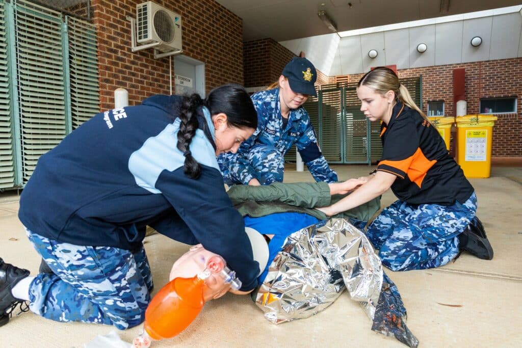 (l-r) Medical Technician, Leading Aircraftwoman Rebecca Saltmer takes Air Force Indigenous Youth Program participants Abby Morton and Indiana Baines through a medical emergency response scenario as part of an interactive display provided by the Pearce Health Centre at RAAF Base Pearce, Western Australia.